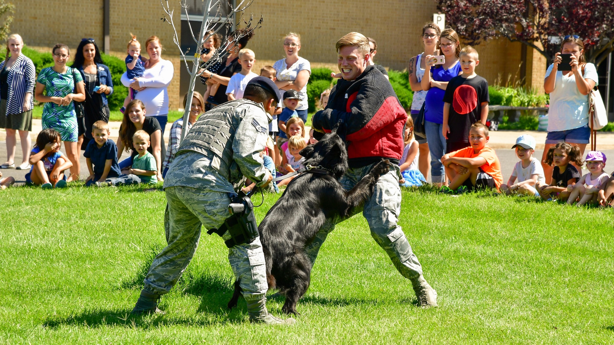 Senior Airman Damien Clayton plays the role of decoy for 75th Security Forces dog handler Senior Airman Ricky Rada and military working dog Bak during a 'Military in Action' demonstration, Hill Air Force Base, Utah, July 18, 2017. Event attendees were given demonstrations and access to equipment by units from across Hill AFB.  (U.S. Air Force photo/R. Nial Bradshaw)