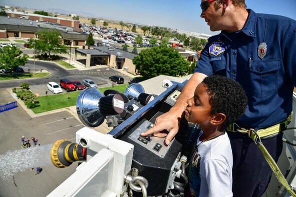 Captain Richard Partington, 775th Civil Engineering Squadron, shows Ilias Braxton how to operate a water cannon during a 'Military in Action event,' Hill Air Force Base, Utah, July 18, 2017. Event attendees were given demonstrations and access to equipment by units from across Hill AFB. (U.S. Air Force photo/R. Nial Bradshaw)