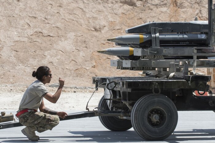 Staff Sgt. Carissa Fall, 332nd Expeditionary Maintenance Squadron precision guided munitions crew chief, guides an airman as he loads missiles on a trailer, July 7, 2017, in Southwest Asia. The squadron builds and maintains a variety of munitions to support F-15E Strike Eagles and MQ-9 Reapers. Air Force photo by Senior Airman Damon Kasberg