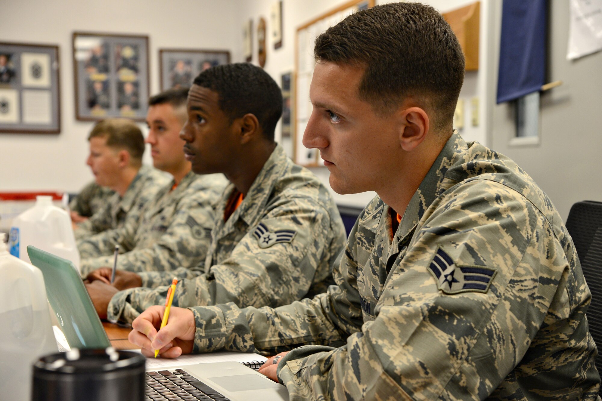 From left, Senior Airmen James, 552nd Aircraft Maintenance Squadron; Boone Epperson, 72nd Force Support Squadron; Kevin, 552nd Aircraft Maintenance Squadron; and Nicholas, 552nd Maintenance Squadron, with Class 17-E Delta Flight, take notes during an Introduction to Negotiation class. (Air Force photo by Kelly White)