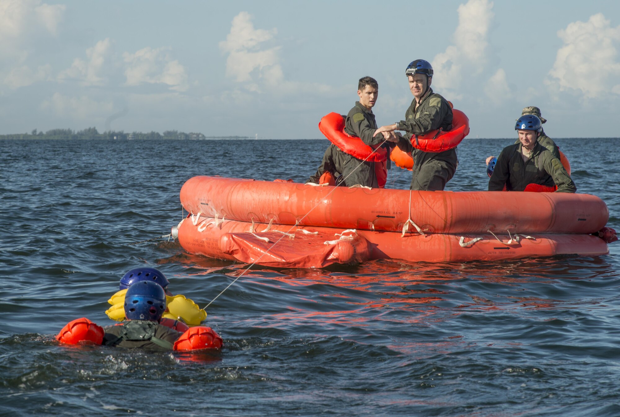 Service members from the Joint Communications Support Element and the 6th Air Mobility Wing swim to a raft and help each other onto a raft during a joint water survival exercise in Tampa Bay, Fla., July 18, 2017.  Once they all were on the raft, they began to simulate how to meet their basic needs of food, water, shelter and evasion. (U.S. Air Force photo by Senior Airman Mariette Adams)