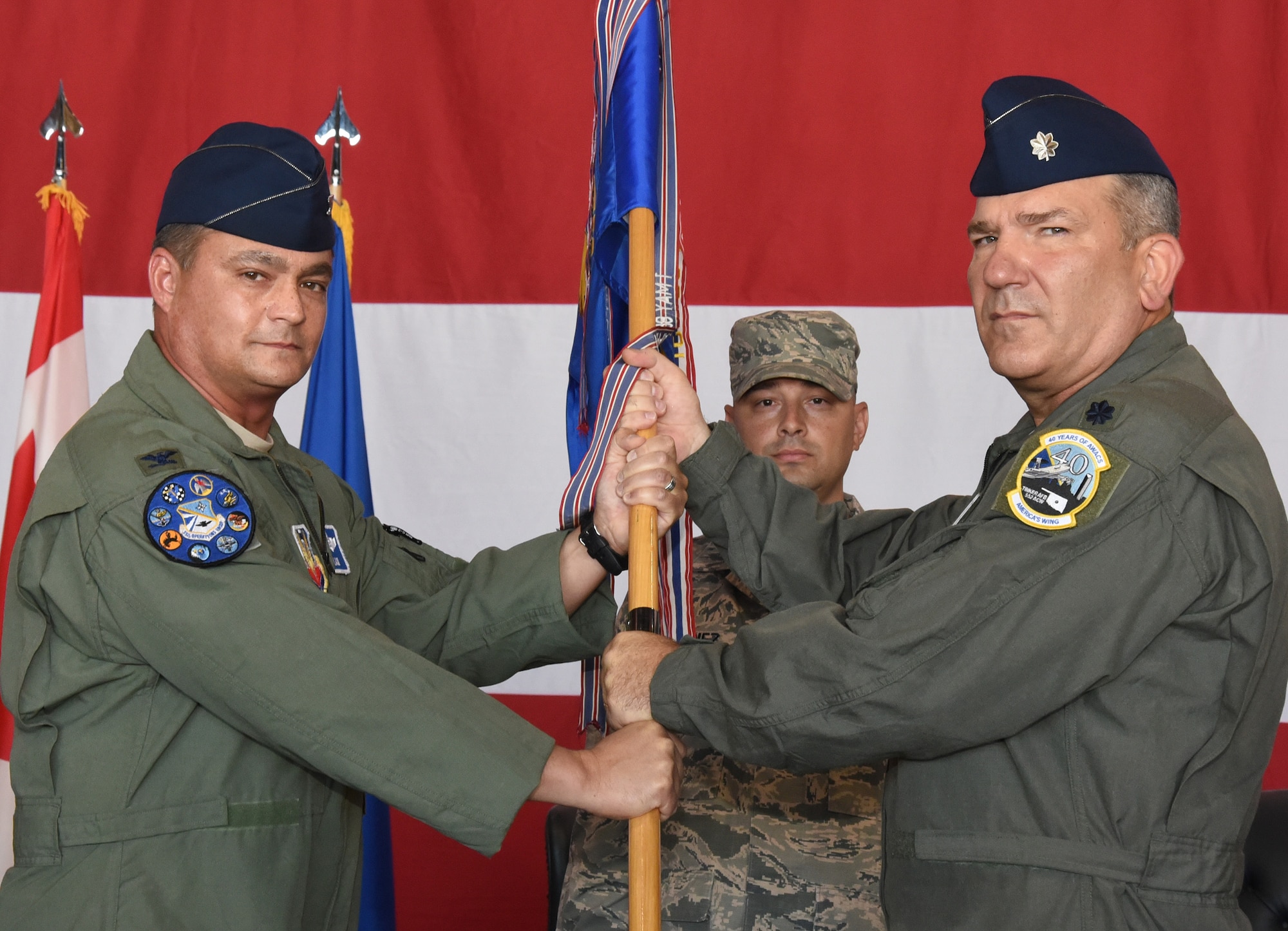 Lt. Col. Kirk Hansen, right, incoming commander of the 552nd Training Squadron accepts the unit guidon from Col. Richard Land III, 552nd Operations Group commander, during a change of command ceremony July 12, in Dock 2 of Hangar 230. Waiting to receive the guidon is Master Sgt. Antonio Quinonez, 552nd TRS first sergeant.