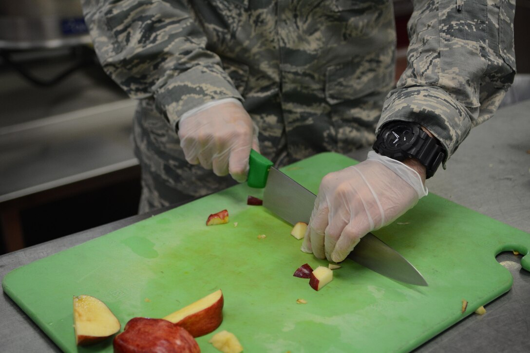 A services Airman cuts apples during meal preparation for Northern Lightning 2017 participants at Volk Field Air National Guard Base, Camp Douglas, Wis., May 9, 2017. The 40 services Airmen and Soldiers from across the nation prepared meals for approximately 6,500 exercise participants during the two-week exercise. (U.S. Air National Guard photo by Staff Sgt. Andrea F. Rhode)