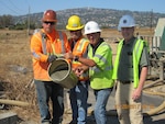 DLA Energy Installation Support for Energy Facility Manager Todd Williams (second from right) and DLA Energy Engineering Division Chief John Cummings (right) pour foam crete into Tank 17, the last tank to be closed at DFSP San Pedro, July 20. 