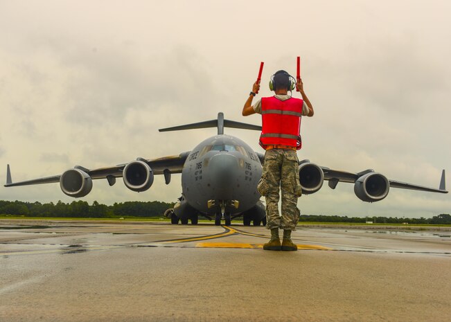 Airman 1st Class Steven Arroyo-Rivera, 437th Aircraft Maintenance Squadron crew chief, directs a C-17 Globemaster III on the flightline at Joint Base Charleston, S.C. July 17, 2017. The C-17’s airlift capabilities are used to deploy U.S. armed forces anywhere in the world within hours. Additionally the C-17’s help sustain troops in conflict, humanitarian, airlift, and airdrop efforts.