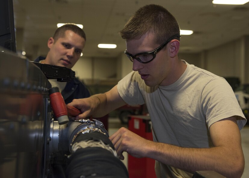Tech. Sgt. David Harris, 141st Aircraft Ground Equipment Craftsman, trains Senior Airman Michael Smith, 141st AGE journeyman, while testing the hose fittings on a hydraulic cart July 19, 2017, at Fairchild Air Force Base, Washington. Hydraulic carts are used to test and pressurize aircraft systems such as landing gear and boom pod hatches. (U.S. Air Force photo / Airman 1st Class Ryan Lackey)