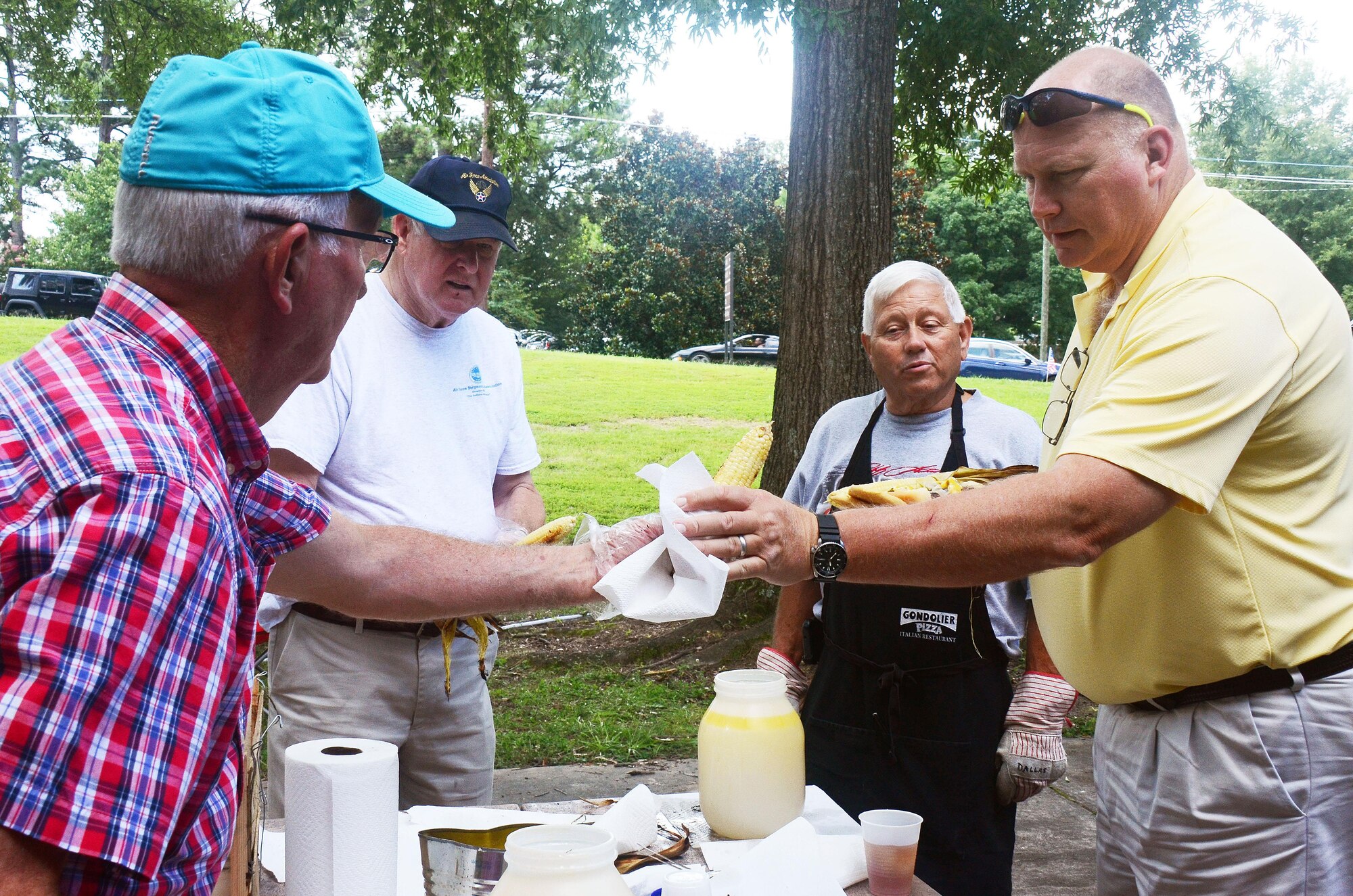 Tommy Wiggington, retired Chief Master Sgt. David Curtis, and retired Chief Master Sgt. Dallas Godfrey serve ears of corn to people attending the annual Corn and Sausage Roast held on Dobbins Air Reserve Base, Ga. July 19, 2017. The event's proceeds, along with assistance from the Dobbins Thrift Store, benefit the Dobbins Emergency Relief Fund. (U.S. Air Force photo/Don Peek) 