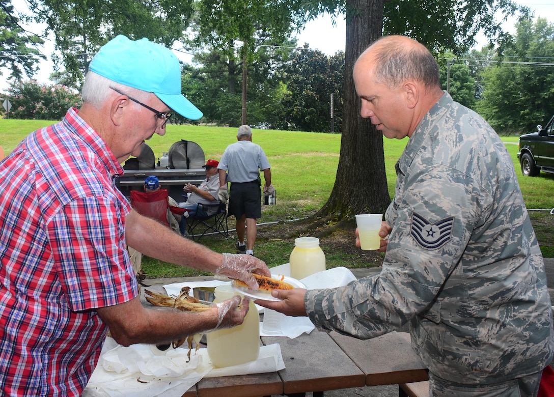 Tommy Wiggington serves up an ear of corn to Tech. Sgt. Blane Lopez from the 80th Aerial Port Squadron, at the annual Corn and Sausage Roast held on Dobbins Air Reserve Base, Ga. July 19, 2017. The event's proceeds, along with assistance from the Dobbins Thrift Store, benefit the Dobbins Emergency Relief Fund. (U.S. Air Force photo/Don Peek)