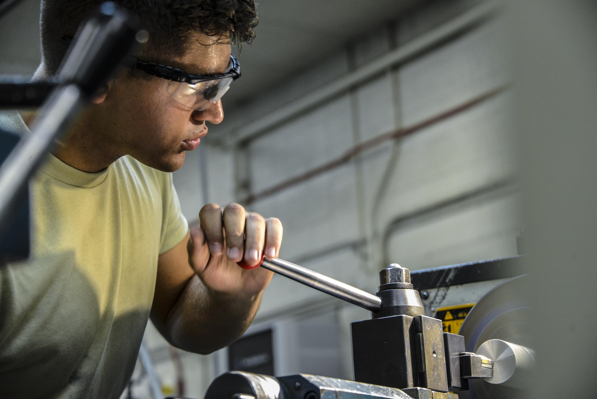 Airman 1st Class Logan Mejia, 56th Equipment Maintenance Squadron aircraft metals technician, uses a lathe while working with a piece of metal at Luke Air Force Base, Ariz., July 19, 2017. Airmen in metals technology deal with a wide variety of metals and other materials such as phenolic, nylon, delrin and rubber but typical repairs consist of aluminum, titanium, steel or stainless steel. (U.S. Air Force photo/Airman 1st Class Caleb Worpel)