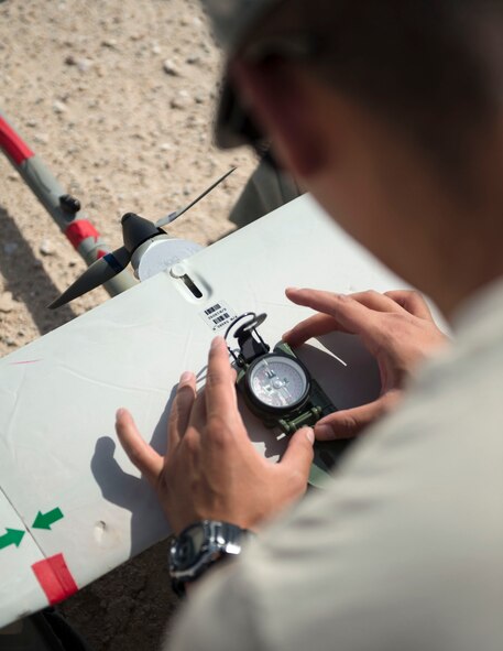 U.S. Air Force Senior Airman Luis Sandoval, a Raven- B operator with 379th Expeditionary Security Forces Squadron, checks the heading of the RQ-11 Raven at Al Udeid Air Base, Qatar, July 3, 2017. The RQ-11 Raven is a small unmanned aircraft system which provides real-time imagery or video for the 379th ESFS. (U.S. Air Force photo by Tech. Sgt. Amy M. Lovgren)
