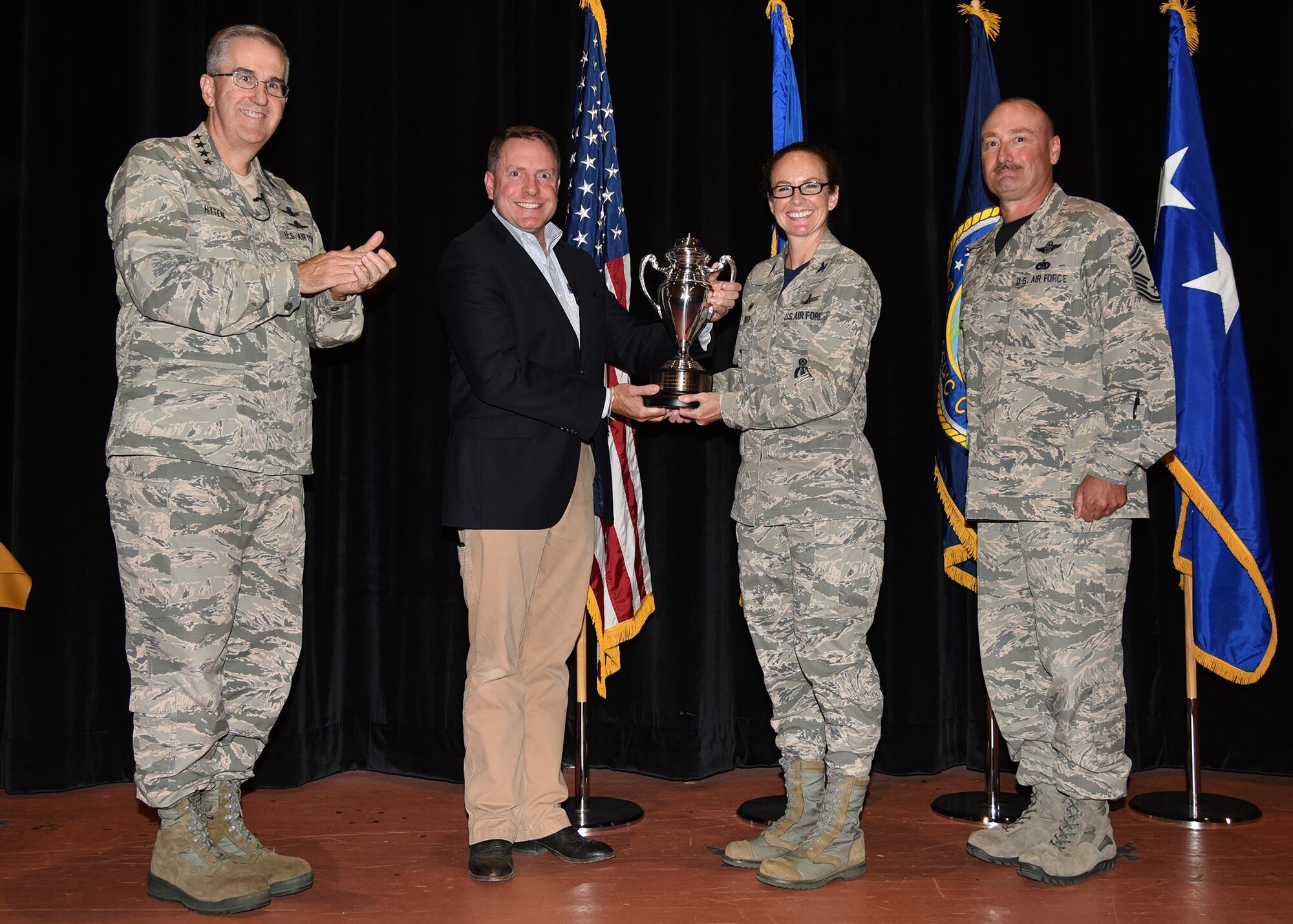 General John Hyten, commander of U.S. Strategic Command, and Tom Janssen, member of the strategic command consultation committee, present the Omaha Trophy to Col. Stacy Huser, 90th Missile Wing commander and incoming Command Chief Master Sgt. Kristian Farve during an all-call at the F. E. Warren Air Force Base, Wyo., theater July 21, 2017. The Omaha Trophy is awarded to the best missile wing in USSTRATCOM. (U.S. Air Force photo by Glenn S. Robertson)