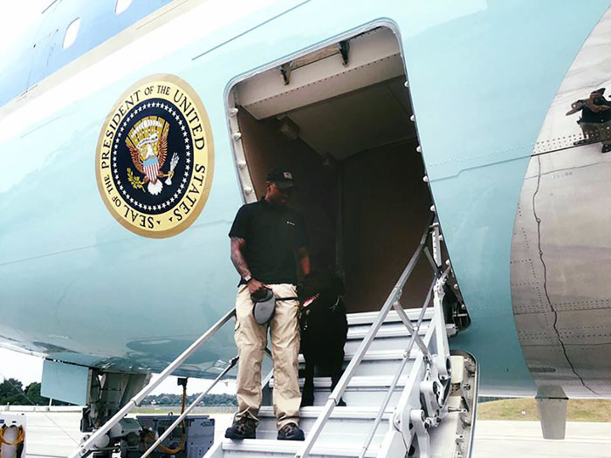 U.S. Air Force Staff Sgt. Dominick Young, 100th Security Forces Squadron Military Working Dog handler, and partner MWD Brock pose for a photo on the steps of Air Force One during a recent detail in support of the president of the United States visit to the G20 Summit in Hamburg, Germany, in July 2017. The MWD team represented RAF Mildenhall in support of the mission and worked alongside Secret Service dog teams. Brock is a Giant Schnauzer and the only one in the Department of Defense. (Courtesy photo)