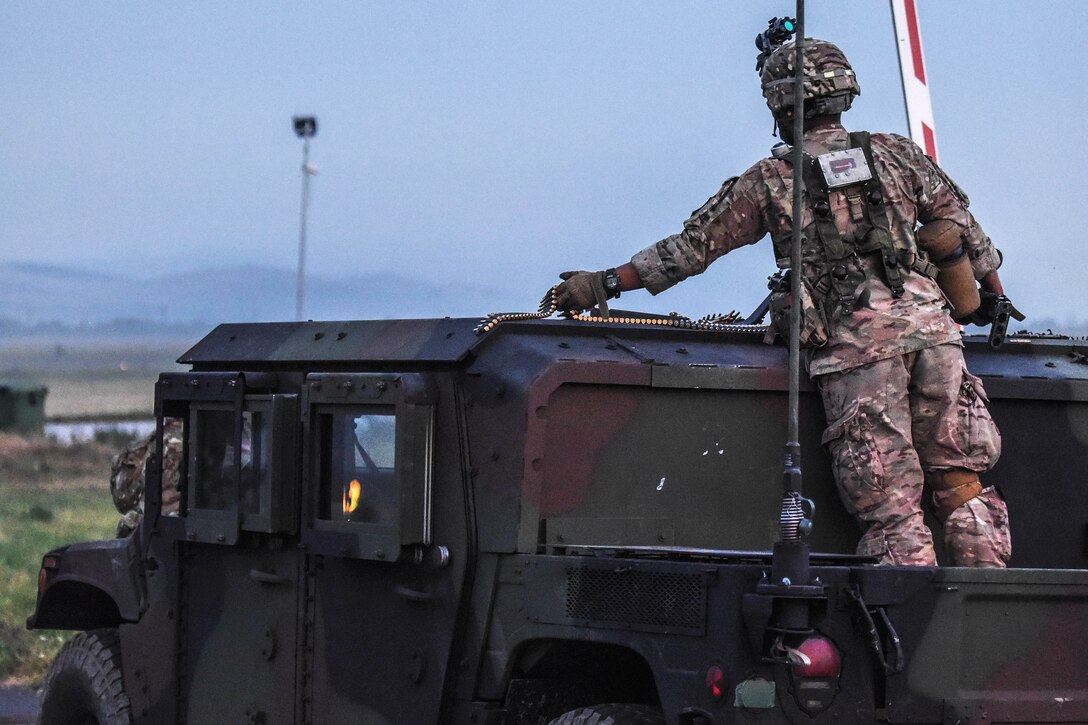 A soldier prepares to load an ammo belt into a machine gun from the top of a tactical vehicle  during Exercise Saber Guardian 17 in Turzii, Romania, July 22, 2017. Army photo by Sgt. David Vermilyea