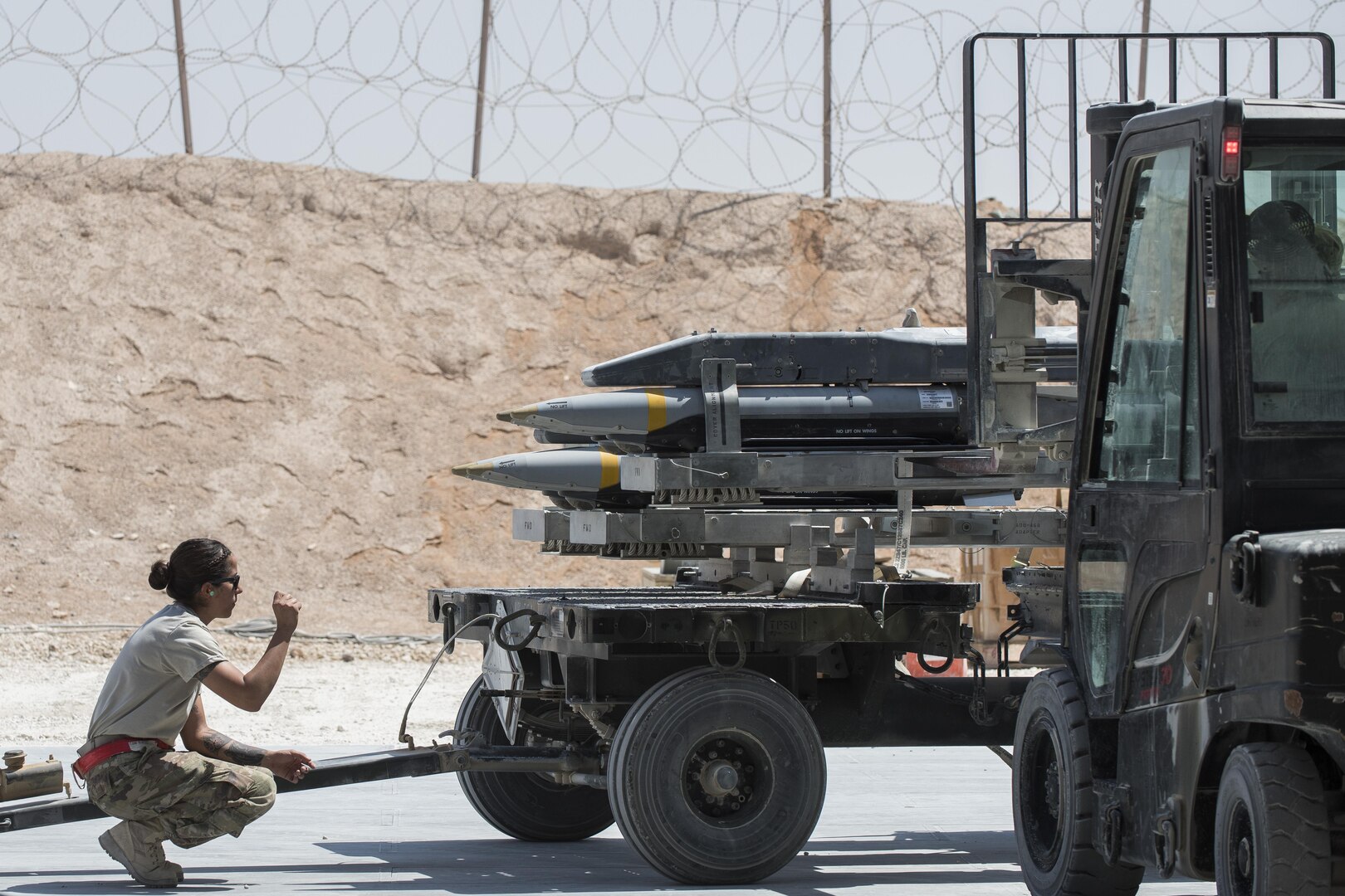 Staff Sgt. Carissa Fall, 332nd Expeditionary Maintenance Squadron precision guided munitions crew chief, guides an Airman as he loads missiles on a trailer July 7, 2017, in Southwest Asia. The squadron builds and maintains a variety of munitions to support F-15E Strike Eagles and MQ-9 Reapers. (U.S. Air Force photo/Senior Airman Damon Kasberg)