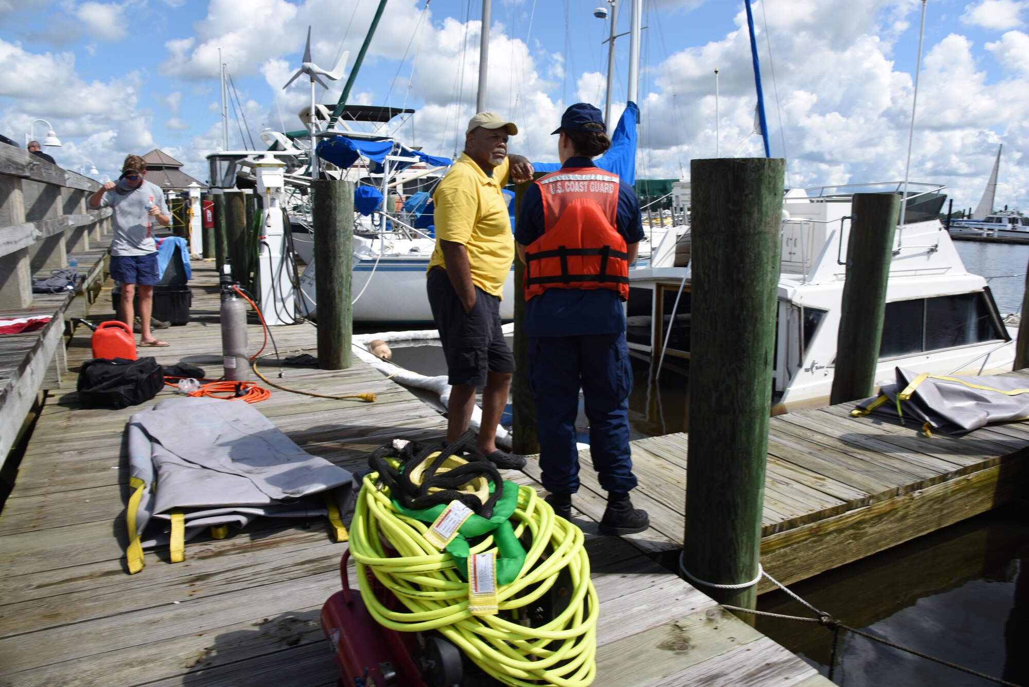 Ron Yates, retired technical sergeant, speaks with Petty Officer 3rd Class Lisa Ball, Coast Guard Mobile Sector Incident Management Division marine science technician, Mobile, Al., at the marina July 19, 2017, on Keesler Air Force Base, Miss. Several agencies gathered to ensure appropriate guidelines and safety procedures were followed prior to retrieving Yates’ sunken boat. (U.S. Air Force photo by Kemberly Groue)
