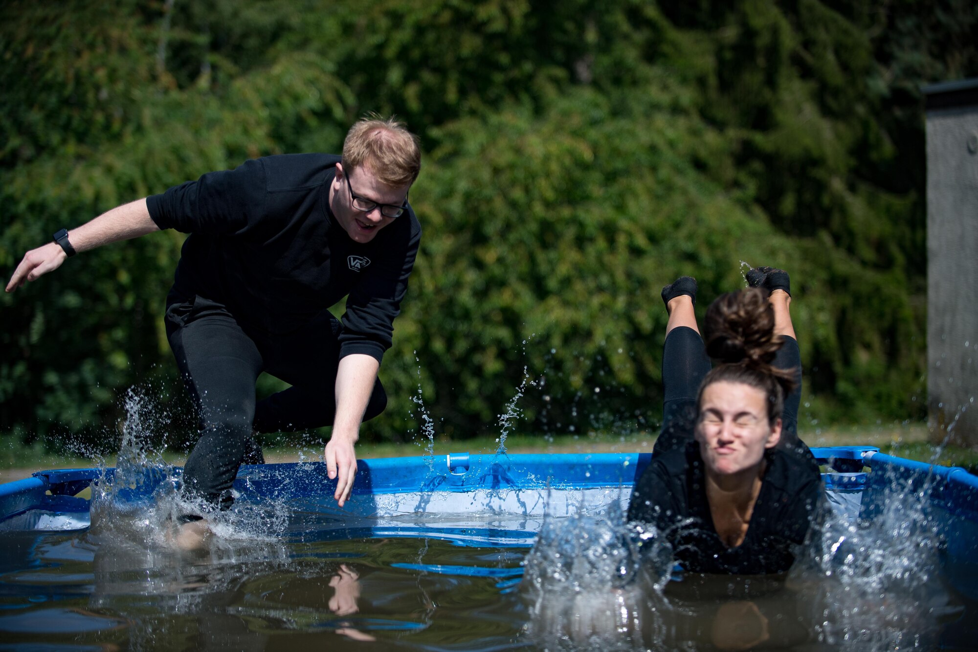 U.S. Air Force Senior Airman Michael Krawczyk and U.S. Air Force Staff Sgt. Jordan Hebner, both 86th Dental Squadron dental assistants, leap into a pool during the annual Mudless Mudder on Ramstein Air Base, Germany, July 21, 2017. If teams could not clear an obstacle, they were required to perform ten burpees to continue the race. (U.S. Air Force photo by Senior Airman Devin Boyer)
