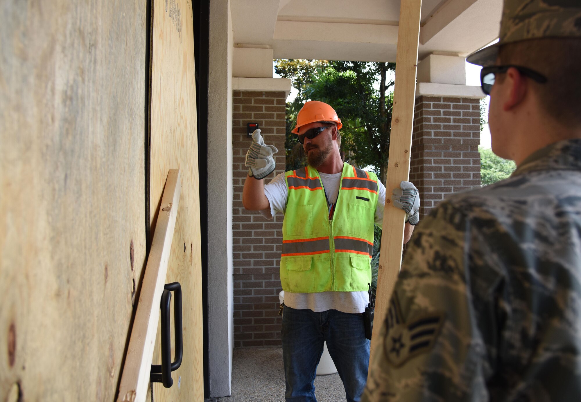Jeremy Railey, Base Operations Support carpenter, explains boarding procedures to Senior Airman Taylor Vann, 81st Training Wing command section administrator, at the 81st TRW headquarters building during a hurricane exercise July 18, 2017, on Keesler Air Force Base, Miss. The purpose of the exercise was to prepare Keesler for the current hurricane season. (U.S. Air Force photo by Kemberly Groue)