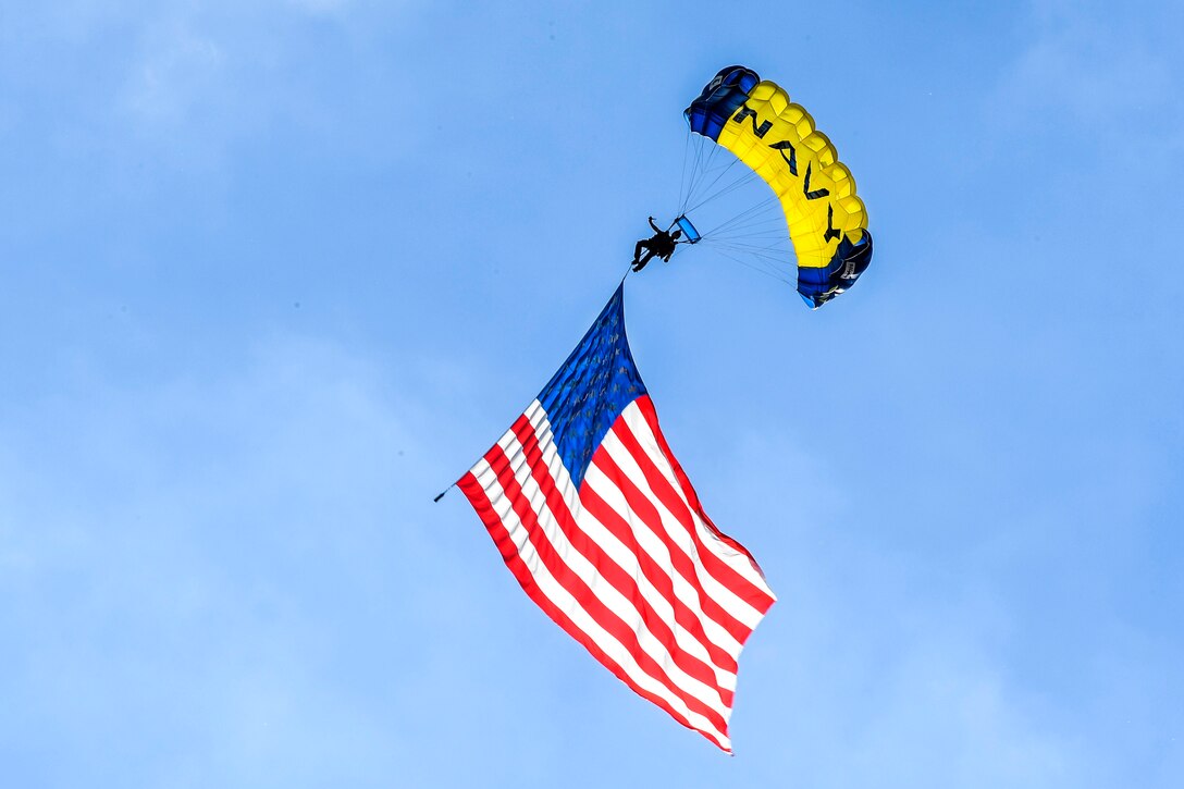 Retired Navy SEAL Jim Woods, a member of U.S. Navy Parachute Team, “The Leap Frogs,” flies the American flag above Elliot Park during a skydiving demonstration at the Summer X Games in Minneapolis, July 14, 2017. Navy photo by Petty Officer 3rd Class Kelsey L. Adams 