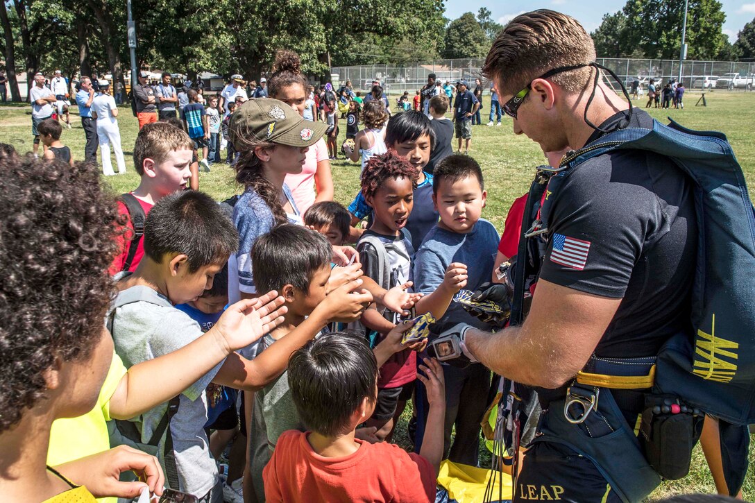 Navy Petty Officer 1st Class Brandon Peterson, a member of U.S. Navy Parachute Team “The Leap Frogs,” gives stickers to young fan after a skydiving demonstration at Hazel Park during Minneapolis/St. Paul Navy Week in Minneapolis, July 17, 2017. Peterson is a Special Warfare operator. Navy photo by Petty Officer 3rd Class Kelsey L. Adams