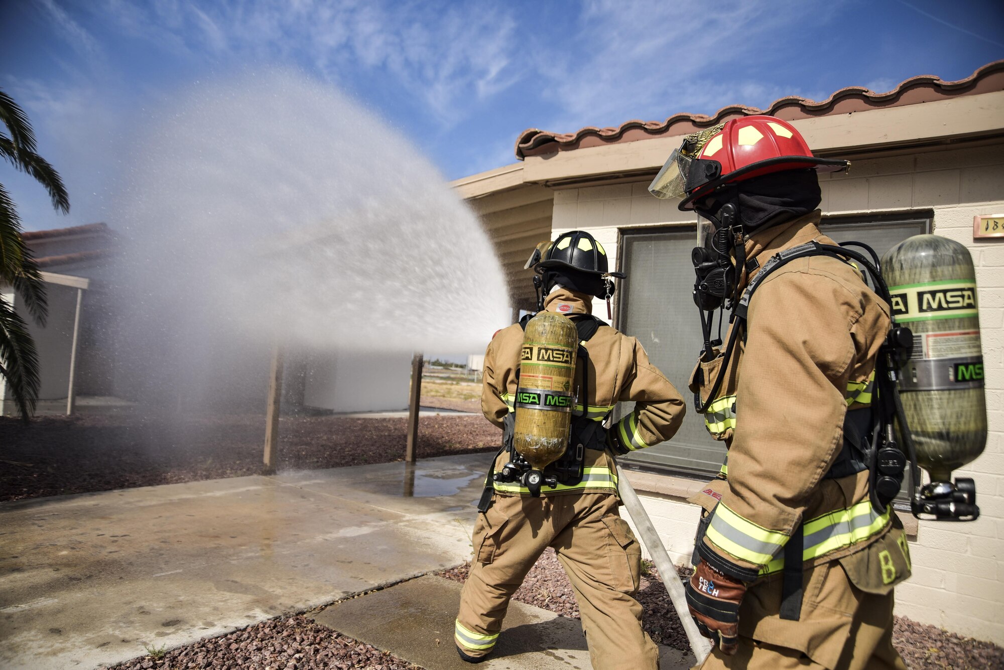 Airman 1st Class Brian Velten, 99th Civil Engineer Squadron firefighter, and Staff Sgt. Blaine Erway, 99th CES firefighter crew chief, use a firehose on a simulated house fire during Red Flag 17-3 at Nellis Air Force Base, Nev., July 18, 2017. Firefighters train for various situations to maintain their emergency response readiness. (U.S. Air Force photo by Airman 1st Class Andrew D. Sarver/Released)