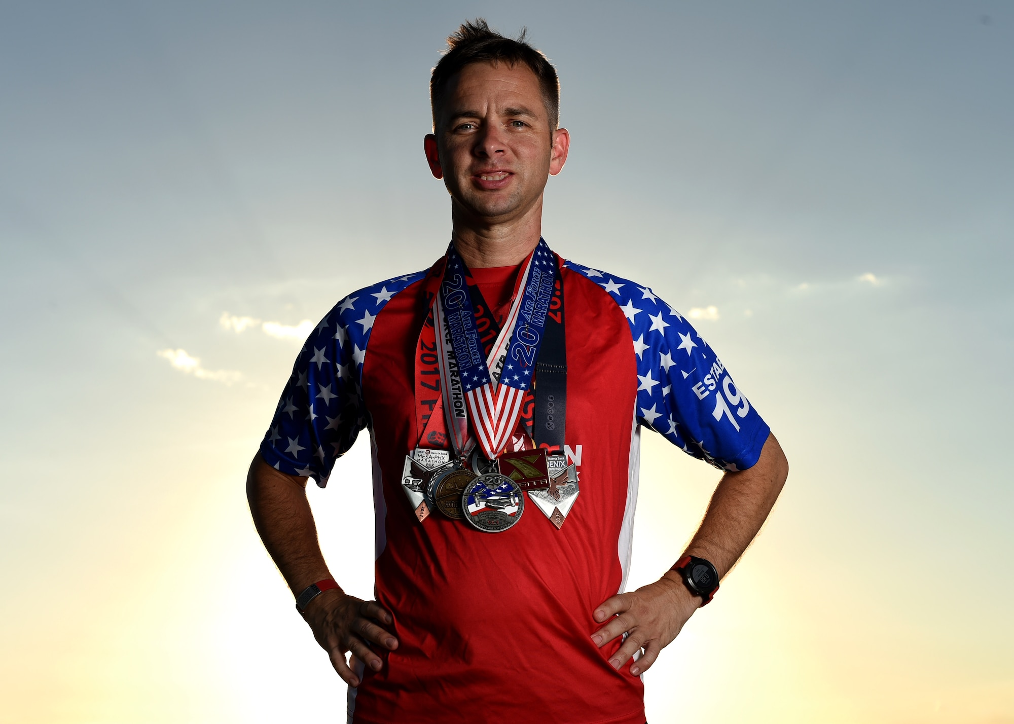 U.S. Air Force Tech. Sgt. Logan Berry, 54th Air Refueling Squadron instructor boom operator, poses while wearing his long-distance running medals, July 20, 2017 at Altus, Oklahoma. After an unsuccessful running portion of a physical training test, Berry motivated himself to become a better runner and has competed in several long-distance running events, including the Air Force Marathon. (U.S. Air Force photo by Senior Airman Kirby Turbak/Released)