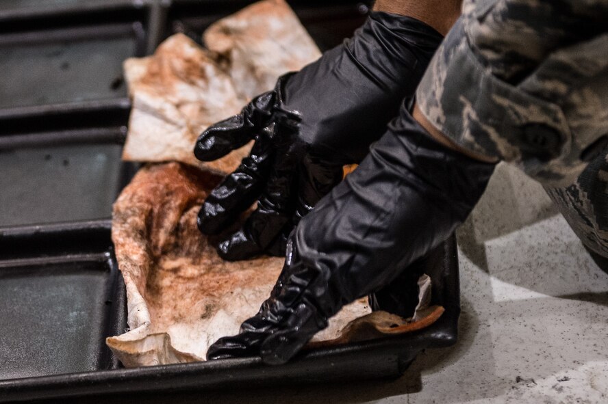 Airman 1st Class Christian Burris, CV-22 Crew Chief, 727 Special Operations Aircraft Maintenance Squadron uses an absorbent pad to clean up used oil. By recycling the used oil, Cannon AFB saves more than $300,000 annually in hazardous waste removal. (U.S. Air Force Photo by Staff Sgt. Charles Dickens/Released)