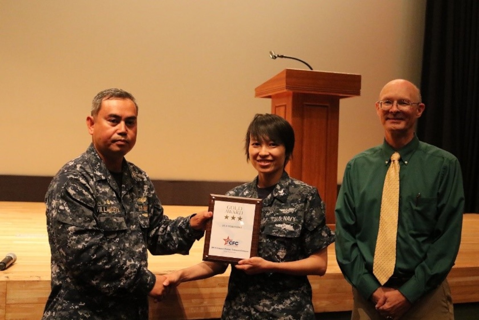 Petty Officer Xiaoyang Xing, center, receives the Combined Federal Campaign Gold Award from DLA Distribution Yokosuka, Japan, commanding officer Cmdr. Nolasco Villanueva, left, and deputy commander Roy Jewell.  At the same time, she was announced as the Meritorious Advancement Program selectee, advancing her to First Class Petty Officer.