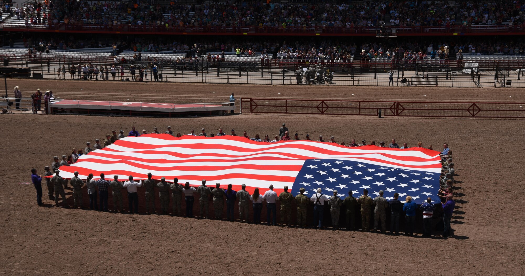 Members of the military and local community present the American flag during Military Monday at Frontier Park in Cheyenne, Wyo., July 24, 2017. The flag presentation is an annual tradition at Cheyenne Frontier Days. This year marks the 150th anniversary of F.E. Warren Air Force Base and the city of Cheyenne. The two communities came together to celebrate during the 121st CFD rodeo and festival. (U.S. Air Force photo by Airman 1st Class Breanna Carter)