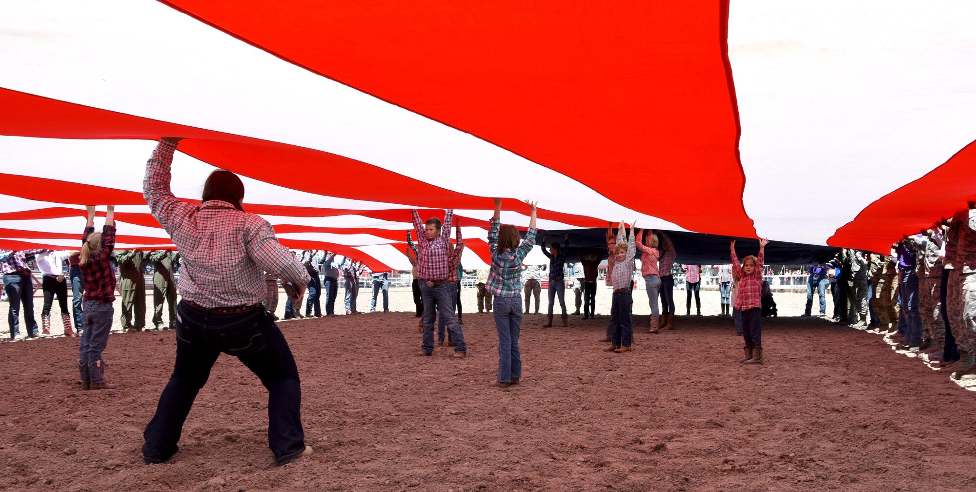 Children from the community stand under the American flag to keep it off the ground during Military Monday at Frontier Park in Cheyenne, Wyo., July 24, 2017. The flag presentation is an annual tradition at Cheyenne Frontier Days. This year marks the 150th anniversary of F.E. Warren Air Force Base and the city of Cheyenne. The two communities came together to celebrate during the 121st CFD rodeo and festival. (U.S. Air Force photo by Airman 1st Class Braydon Williams)