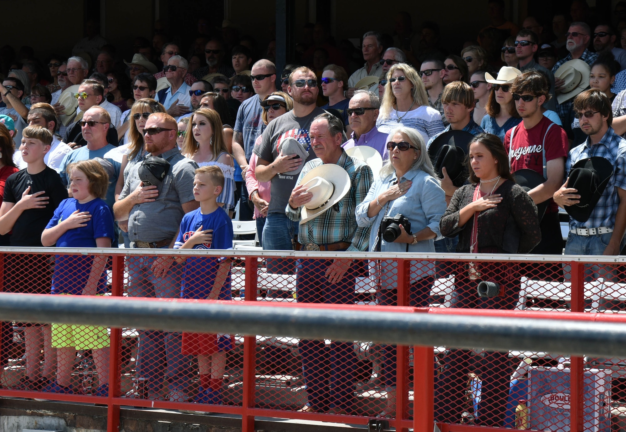 Spectators stand for the national anthem during Military Monday at Frontier Park in Cheyenne, Wyo., July 24, 2017. Cheyenne Frontier Days is Cheyenne’s biggest annual event with hundreds of visitors taking part. This year marks the 150th anniversary of F.E. Warren Air Force Base and the city of Cheyenne. The two communities came together to celebrate during the 121st CFD rodeo and festival. (U.S. Air Force photo by Airman 1st Class Breanna Carter)