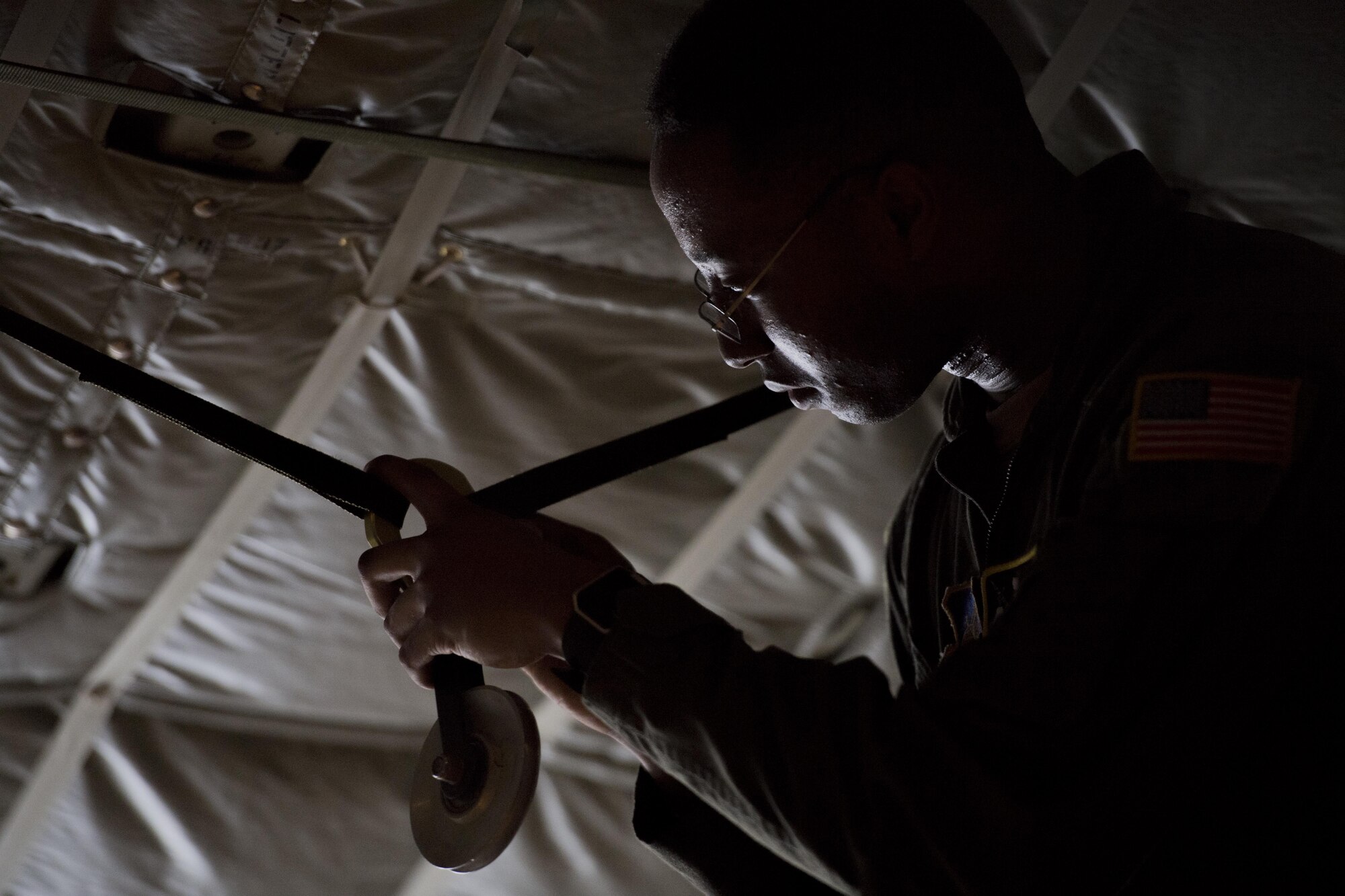 Airman 1st Class Young Achuka, 36th Airlift Squadron C-130J Super Hercules loadmaster, prepares rigging for a bundle drop in a C-130J, July 18, 2017, at Yokota Air Base, Japan. Cargo to be dropped is rigged to ensure the aircrews safety, the cargo properly exits the aircraft and the cargos parachute deploys. (U.S. Air Force photo by Airman 1st Class Donald Hudson)