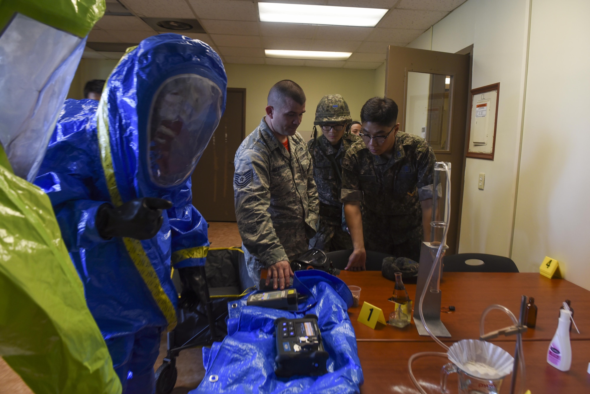 U.S. Air Force Tech. Sgt. Joseph Neejer-Widener, 8th Civil Engineer Squadron emergency management flight noncommissioned officer in charge, center, shows Republic of Korea Air Force Lt. Kim, Kitae, 38th Fighter Group chemical, biological, radiological, and nuclear defense support flight commander, different tools to detect and define substances while performing response operations for a hazardous material incident at Kunsan Air Base, Republic of Korea, July 21, 2017. The training scenario gave participants a better understanding of HAZMAT response equipment and operations. (U.S. Air Force photo by Senior Airman Michael Hunsaker/ Released)
