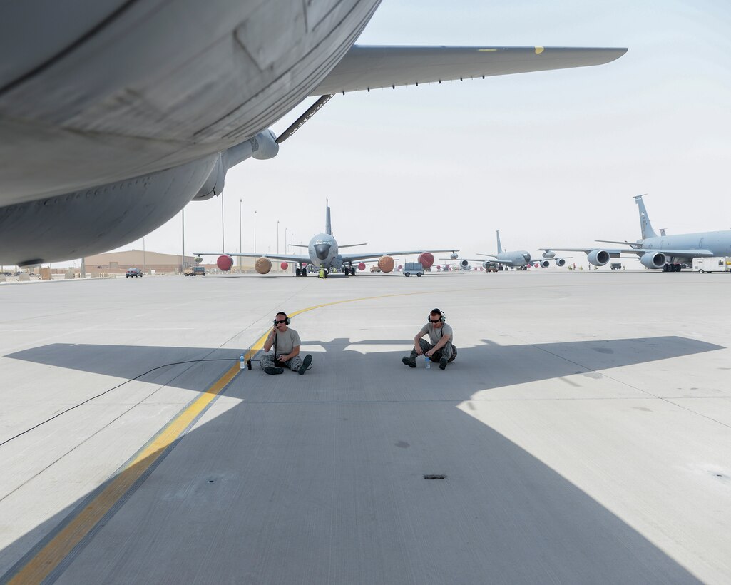 U.S. Air Force Technical Sgt. Korey Barber, left, crew chief, and Airman 1st Class Cormac Miller, right, hydraulic apprentice, both assigned to the 340th Expeditionary Aircraft Maintenance Unit, find a bit of shade beneath the tail of a KC-135 Stratotanker as they wait for final preparations prior to launching the aircraft from Al Udeid, Air Base, Qatar, July 7, 2017. The members of the 340th and 22nd EAMUs face minute-by-minute challenges in the sweltering heat on the runway as they work to keep a fleet of KC-135 Stratotankers ready to fly. (U.S. Air National Guard photo by Tech. Sgt. Bradly A. Schneider/Released)