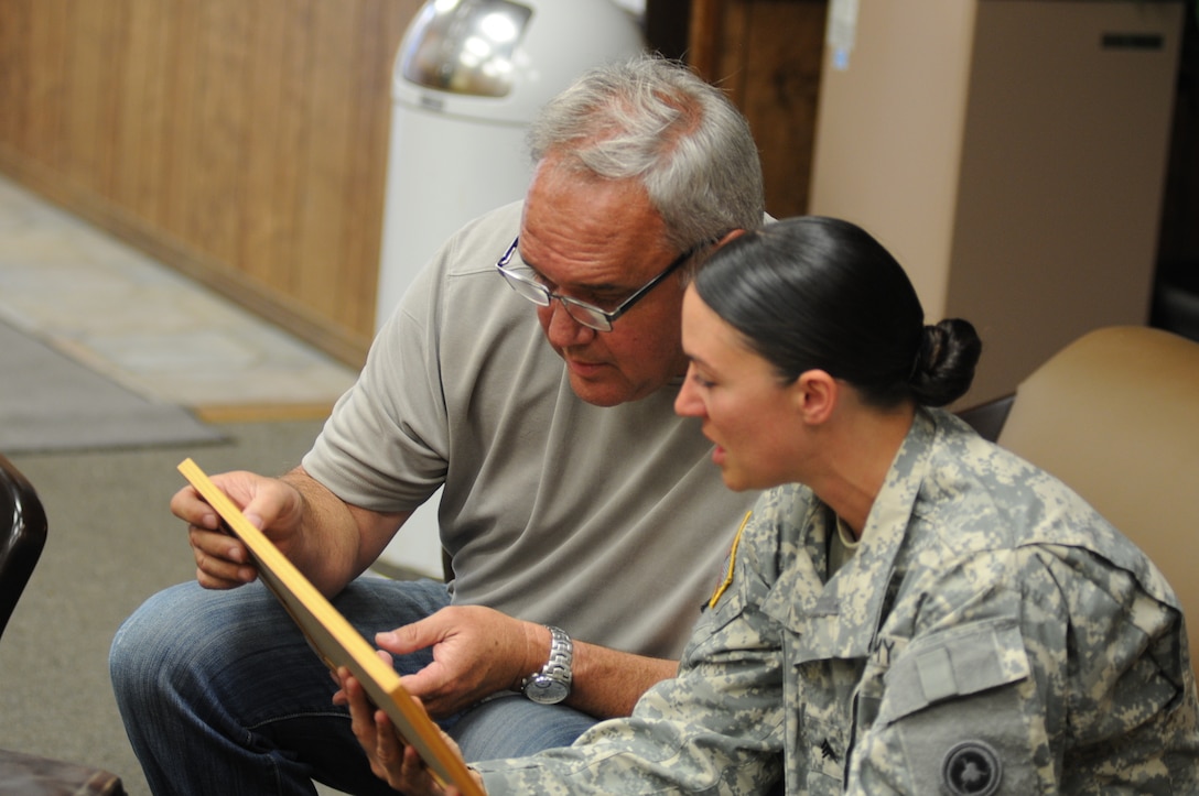 Sgt. Angela Myers, 311th ESC ammunition sergeant, looks over photos she's never seen with her Uncle Corey Rose. This is Myers first time meeting her uncle or any biological family. She was raised in foster care.