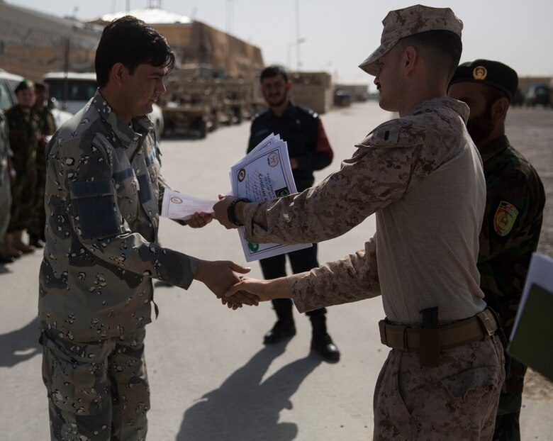 An Afghan National Civil Order Policeman receives his certificate for passing a map class at Bost Airfield, Afghanistan, July 22, 2017. U.S. Marine advisors with Task Force Southwest conducted a three-week map reading class focusing on terrain association, plotting and finding grid coordinates on a map. (U.S. Marine Corps photo by Justin T. Updegraff)