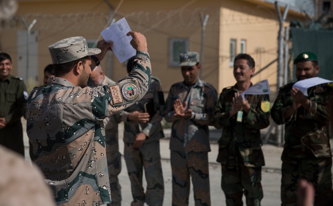 An Afghan National Civil Order Policeman shows his certificate to his Afghan National Defense and Security Force partners at Bost Airfield, Afghanistan, July 22, 2017. U.S. Marine advisors with Task Force Southwest conducted a three-week map reading class focusing on terrain association, plotting and finding grid coordinates on a map. (U.S. Marine Corps photo by Justin T. Updegraff)
