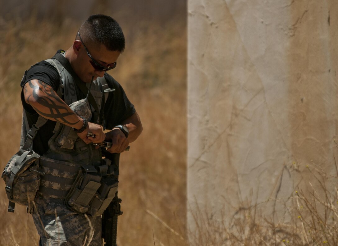 Army Reserve Sgt. Jc Pineda, a military police officer with the 96th Military Police Company, 96th Military Police Battalion, corrects a magazine malfunction before his unit attacks other Reserve Command Soldiers while roleplaying as enemy troops during a training exercise at Niscoln, a small mock village on Fort Hunter Liggett, Calif., July 20, 2017. The other Reserve Soldiers, members of the 344th Military Police Company, 485th Chemical Battalion, and 382nd Military Police Battalion, are training as part of Combat Support Training Exercise 91-17-03. Nearly 5,400 service members from the U.S. Army Reserve Command, U.S. Army, Army National Guard, U.S. Navy, and Canadian Armed Forces are training at Fort Hunter Liggett as part of the 84th Training Command’s CSTX 91-17-03 and ARMEDCOM’s Global Medic; this is a unique training opportunity that allows U.S. Army Reserve units to train alongside their multi-component and joint partners as part of the America’s Army Reserve evolution into the most lethal Federal Reserve force in the history of the nation. (U.S. Army Reserve photo by Sgt. David L. Nye, 301st Public Affairs Detachment)