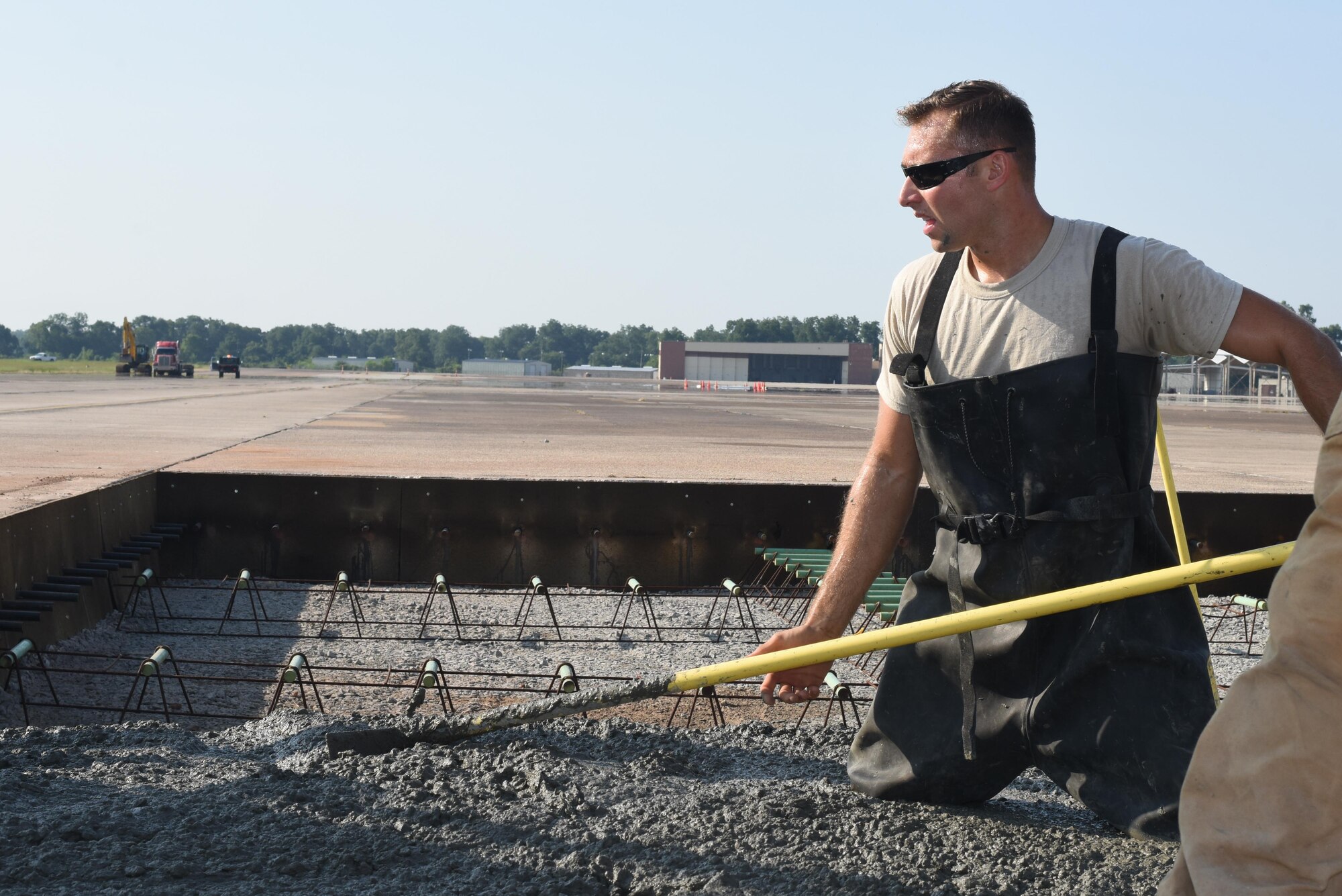 Staff Sgt. Jon Martinez, assigned to the 2nd Civil Engineer Squadron Dirt Boyz, stands in wet concrete as he evens it out at Barksdale Air Force Base, La., July 18, 2017. Martinez wore rubber overalls in order to keep the concrete’s corrosive chemicals off his skin. (U.S. Air Force Photo/Airman 1st Class Sydney Bennett)