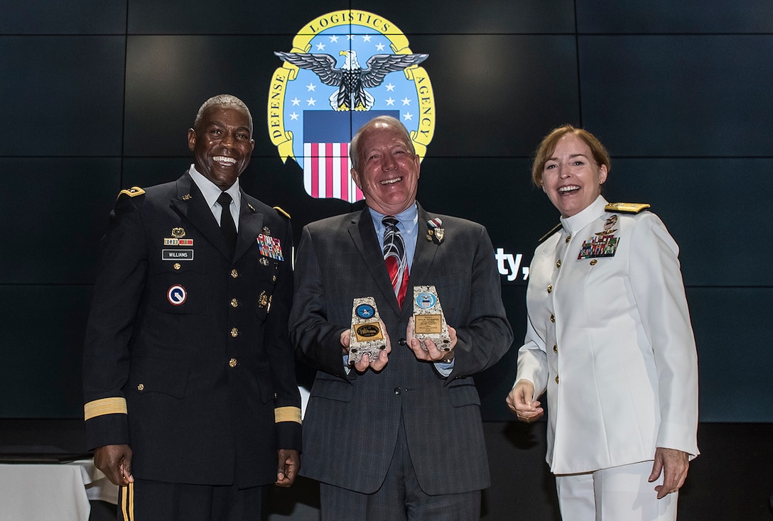 Defense Logistics Agency Director Army Lt. Gen. Darrell Williams (left) presented DLA Land and Maritime Deputy Commander James McClaugherty (center) with memento bookends on behalf of the agency during McClaugherty's retirement ceremony July 20. McClaugherty completed 47 years of military and federal civilian service and worked with nine Land and Maritime commanders including current commander Navy Rear Adm. Michelle Skubic (right).