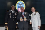 Defense Logistics Agency Director Army Lt. Gen. Darrell Williams (left) presented DLA Land and Maritime Deputy Commander James McClaugherty (center) with memento bookends on behalf of the agency during McClaugherty's retirement ceremony July 20. McClaugherty completed 47 years of military and federal civilian service and worked with nine Land and Maritime commanders including current commander Navy Rear Adm. Michelle Skubic (right).