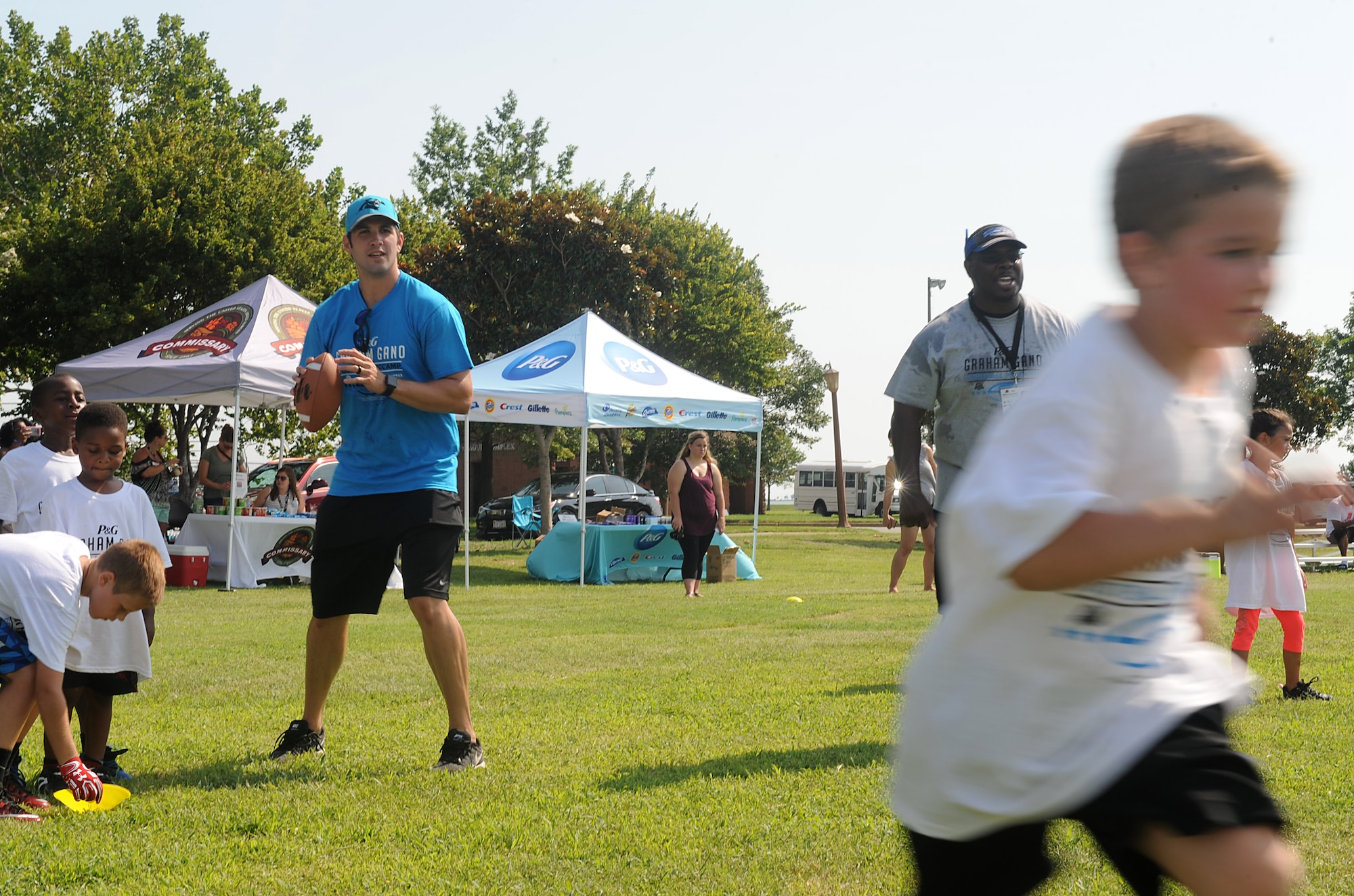 (Left) Graham Gano, Carolina Panthers placekicker, prepares to throw a football to a military child during a youth football camp at Joint Base Langley-Eustis, Va., July 19, 2017. The football camp allowed the children to not only meet Gano but to also drill and train alongside him. (U.S. Air Force photo/Staff Sgt. Brittany E. N. Murphy)