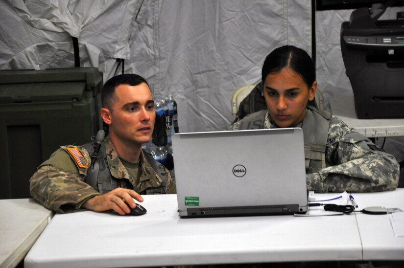 1st Lt. Rene Casas, strength manager with the with the 166th Regional Support Group out of Fort Buchanan, Puerto Rico, assists Spc. Valerie Morales, a human resources specialist with the 166th RSG, with a spreadsheet at the Joint Mortuary Affairs Exercise Tactical Operations Center on Fort Pickett, Virginia, July 17, 2017. The Army Reserve Soldiers are participating in the 2017 JMAX along with active Army Soldiers, the Air Force and Marines.