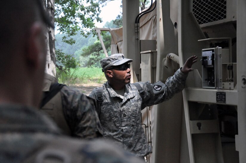 Sgt. 1st Class Luis Burgos, a mortuary affairs collection point NCOIC with the 311th Quartermaster Company out Ramey Base, Puerto Rico, shows a group of mortuary affairs Marines the cooling components outside a Mobile Integrated Remains Collection System at Fort Pickett, Virginia, July 17, 2017. The Army Reserve Soldier is participating in the 2017 Joint Mortuary Affairs Exercise along with active Army Soldiers, the Air Force and Marines.