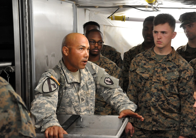 Sgt. 1st Class Luis Burgos, a mortuary affairs collection point NCOIC with the 311th Quartermaster Company out Ramey Base, Puerto Rico, shows a group of mortuary affairs Marines the refrigeration unit inside a Mobile Integrated Remains Collection System at Fort Pickett, Virginia, July 17, 2017. The Army Reserve Soldier is participating in the 2017 Joint Mortuary Affairs Exercise along with active Army Soldiers, the Air Force and Marines.