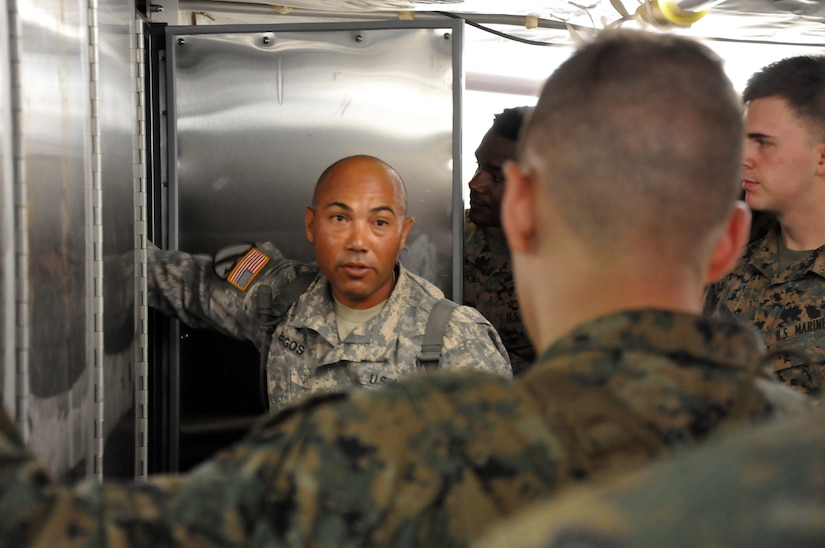 Sgt. 1st Class Luis Burgos, a mortuary affairs collection point NCOIC with the 311th Quartermaster Company out Ramey Base, Puerto Rico, shows a group of mortuary affairs Marines the refrigeration unit inside a Mobile Integrated Remains Collection System at Fort Pickett, Virginia, July 17, 2017. The Army Reserve Soldier is participating in the 2017 Joint Mortuary Affairs Exercise along with active Army Soldiers, the Air Force and Marines.