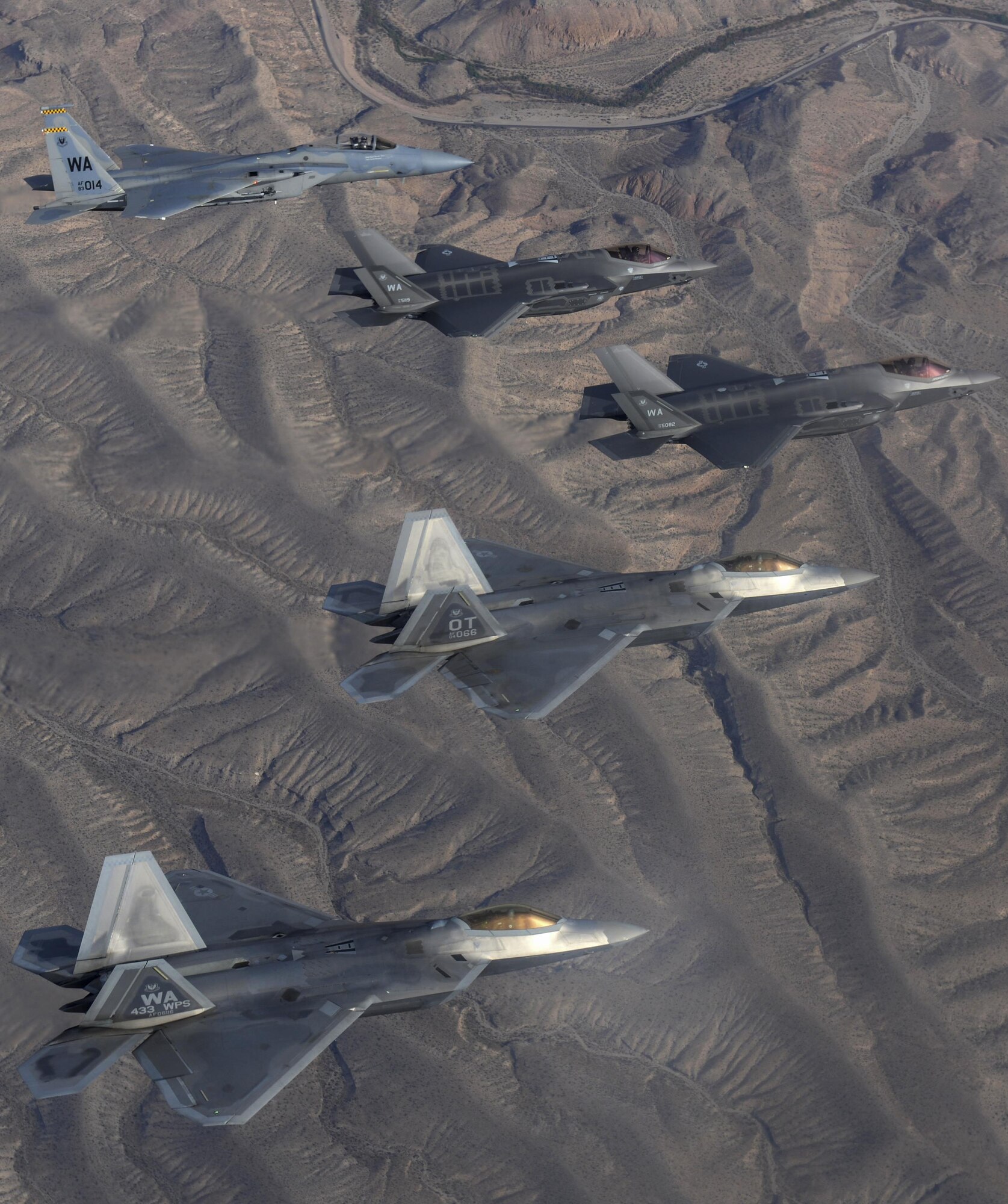 F-35 Lightning II, assigned to the 6th Weapons Squadron, at Nellis Air Force Base, Nevada, F-22 Raptor and an F-15 fighter jets, assigned to the 433rd Weapons Squadron, at Nellis Air Force Base, Nevada, fly in formation over the Nevada Test and Training Range July 10, 2017. The United States Air Force Weapons School teaches graduate-level instructor courses that provide the world's most advanced training in weapons and tactics employment to officers of the combat air forces and mobility air forces. (U.S. Air Force photo by Staff Sgt. Daryn Murphy/Released)