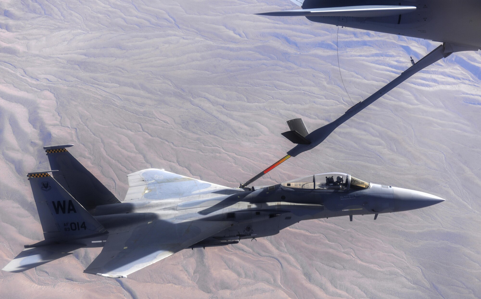 An F-15 fighter jet, assigned to the 433rd Weapons Squadron, at Nellis Air Force Base, Nevada, receives aerial refueling from a KC-135 Stratotanker cargo aircraft assigned to the 509th Weapons Squadron, at Fairchild Air Force Base, Washington, cargo aircraft assigned to the 509th Weapons Squadron, Fairchild Air Force Base, Washington, over the Nevada Test and Training Range July 10, 2017. The United States Air Force Weapons School teaches graduate-level instructor courses that provide the world's most advanced training in weapons and tactics employment to officers of the combat air forces and mobility air forces. (U.S. Air Force photo by Staff Sgt. Daryn Murphy/Released)