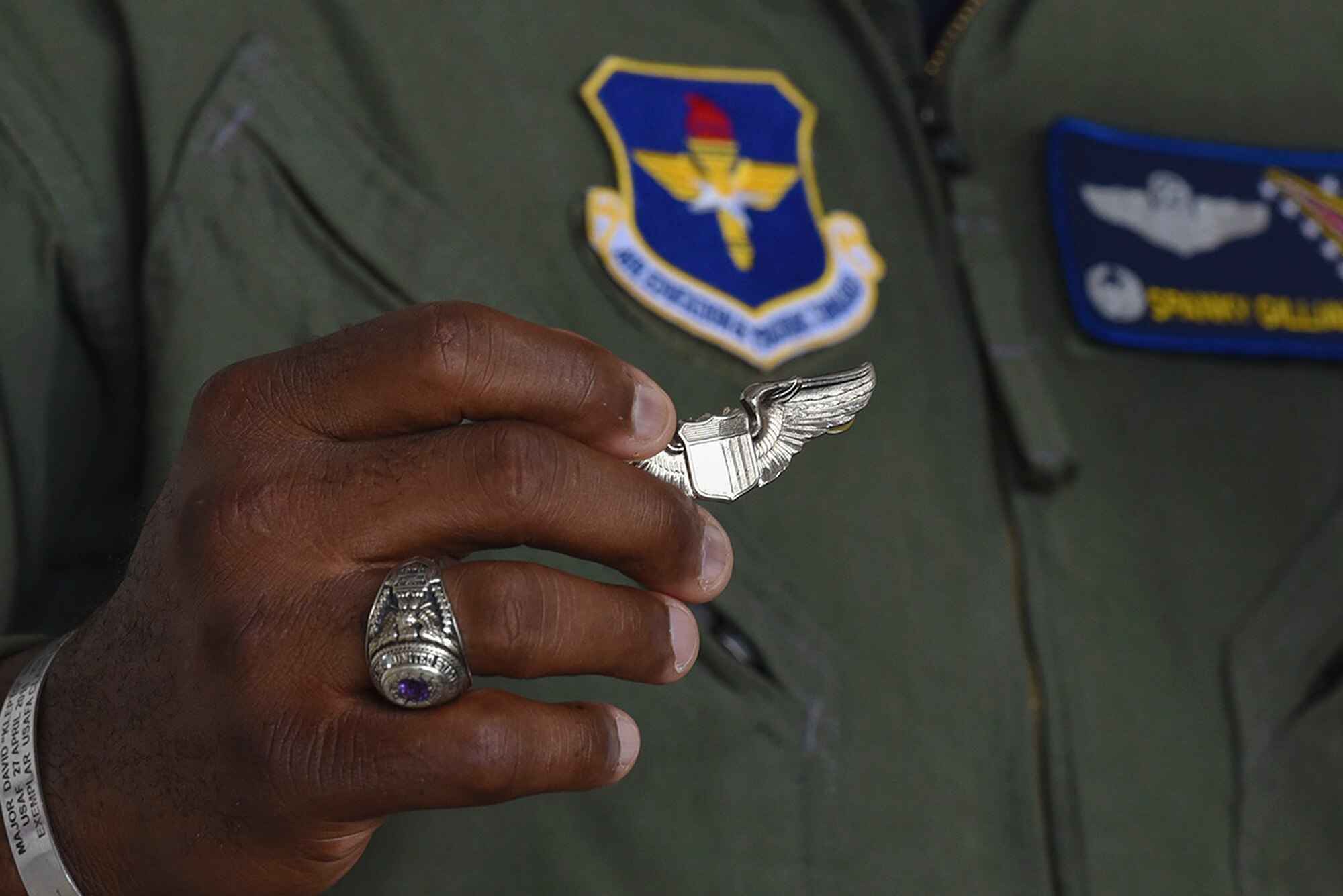 Lt. Col. Charles Gilliam, 48th Flying Training Squadron commander, Columbus Air Force Base, Miss., holds a Silver Wings badge to commemorate the Tuskegee Airmen and explains the significance of their World War II efforts, as a part of the Eyes Above the Horizon diversity outreach program, July 22, 2017, in Valdosta, Ga. The Valdosta Regional Airport welcomed approximately 100 10-19-year-olds as they took the Valdosta skies to commemorate the 76th Anniversary of the historic Tuskegee Airmen. The program focuses on mentoring and familiarizing underrepresented minorities with basic flying fundamentals. (U.S. Air Force photo by Senior Airman Greg Nash) 