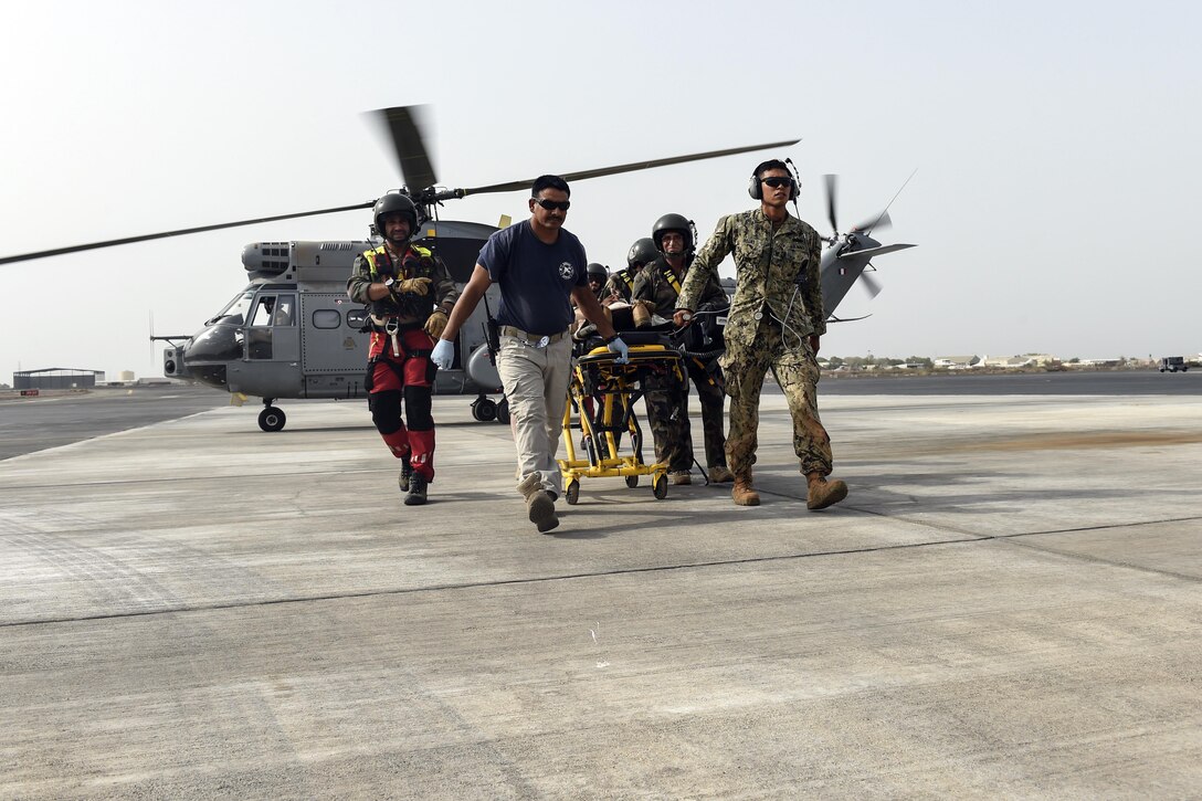 Navy Petty Officer 3rd Class David Rojas, assigned to Naval Mobile Construction Battalion One, a maneuver unit of the Combined Joint Task Force-Horn of Africa, along with emergency medical services personnel and members of the French Air Force Tactical Airlift Squadron 88, transport a mock patient from a SA 330 Puma helicopter across the flightline during a bilateral exercise with French forces at Camp Lemonnier, Djibouti, July 20, 2017. Air Force photo by Staff Sgt. Eboni Prince