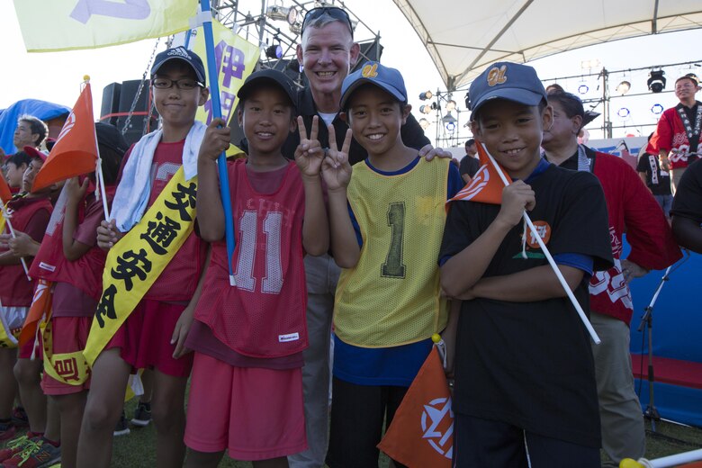 Col. Scott R. Johnson poses with local children during the Torch Lighting Ceremony at the 40th Annual Tedako Matsuri Festival July 22 in Urasoe City, Okinawa, Japan. During this festival, respects are paid to King Eiso, a powerful king of the Ryukyu Kingdom. Johnson is the commanding officer of Headquarters Regiment 3rd Marine Logistics Group, III Marine Expeditionary Force, and Camp Kinser camp commander.